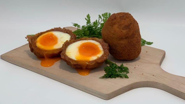 Schottische Eier auf einem Holzbrett angerichtet. Super zum Teilen und ein perfekter Party- und Public viewing-Snack.