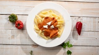 Auf einem Teller angerichtet: Pasta mit einer Tomaten-Paprika-Sauce und Mozzarella