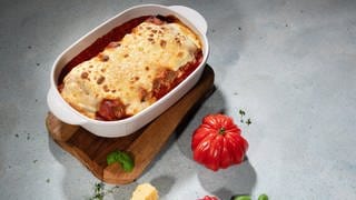 In einer weißen Auflaufform sind Cannelloni mit Merguez-Würsten als Auflauf angerichtet. 