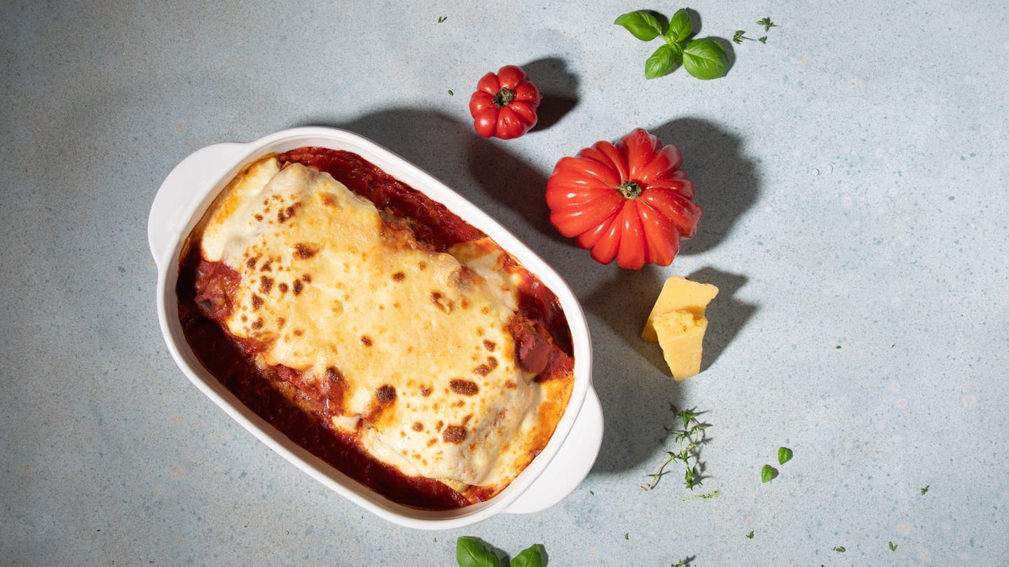 In einer weißen Auflaufform sind Cannelloni mit Merguez-Würsten als Auflauf angerichtet.