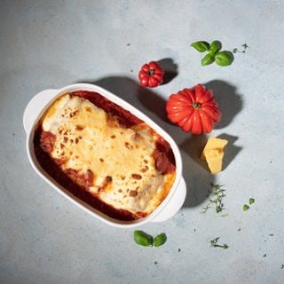 In einer weißen Auflaufform sind Cannelloni mit Merguez-Würsten als Auflauf angerichtet. 