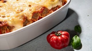 In einer weißen Auflaufform sind Cannelloni mit Merguez-Würsten als Auflauf angerichtet. 