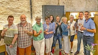 Bei der Weinwanderung im Taubertal ist die Gruppe im Kloster Bronnbach angekommen. Dort gibt es den Kloster-Secco zum Probieren.