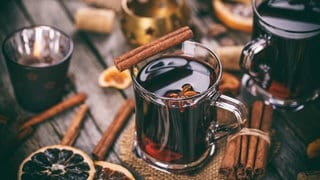 Heißer Glühwein mit Orangenscheiben, Anis und Zimtstangen in einem Glas.