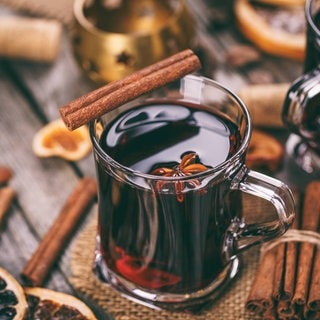 Heißer Glühwein mit Orangenscheiben, Anis und Zimtstangen in einem Glas.