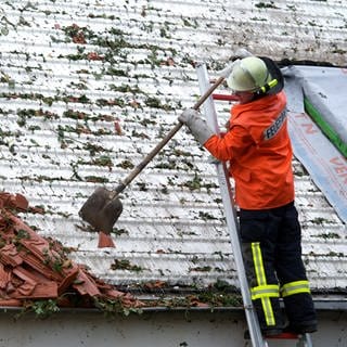 Feuerwehr kehrt Zeigel von kaputtem Dach