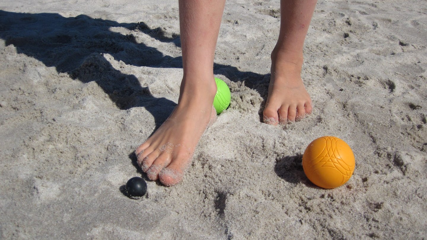 Eine Familie spielt Boccia am Strand.