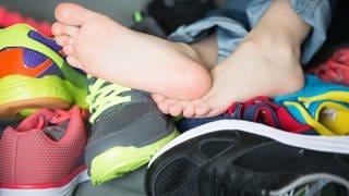 Nackte Füße zwischen verschiedenen Schuhen