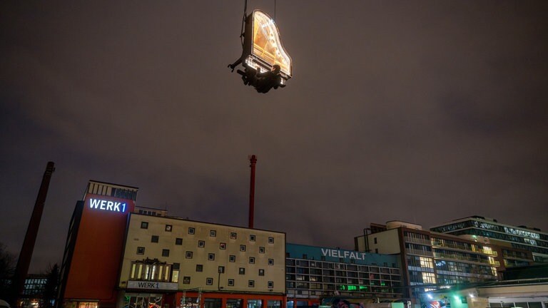 21. Dezember: Künstler Alain Roche liebt es vertikal zu spielen. Sein Plan ist 182 Tage lang jeden Morgen kurz vor Sonnenaufgang ein Klavierkonzert in zehn Meter Höhe zu geben. Und das in München bei jedem Wetter. Dabei sitzt er an seinem beleuchteten Flügel, der von einem Kran gehalten wird. Die Konzerte mit dem Titel "When The Sun Stands Still" sollen ein Unterstützungsprojekt zum Bau des Münchner Konzerthauses sein.