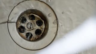 Wasser fließt in einem Abfluss | Diese Hausmittel helfen, wenn der Abfluss stinkt.