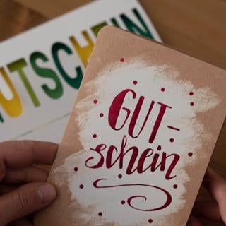 Hand hält Gutschein, Gutschein im Hintergrund