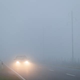 Ein Auto fährt durch dichten Nebel | Das solltet ihr bei Fahrten im Nebel unbedingt beachten