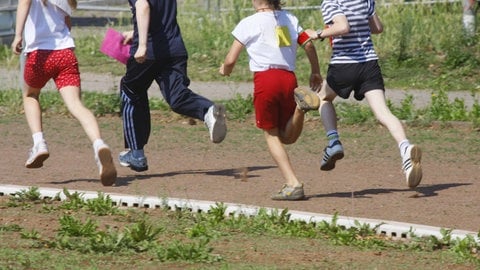 Kinder auf rennen auf einem Sportplatz (Symbolbild) | Grundschüler in Erpel wehren sich gegen Bauschutt auf dem Sportplatz