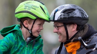 Kleiner Junge und Mann mit Helm | Sicherheitsausrüstung fürs Fahrrad: Helm, Schloss, Kleidung