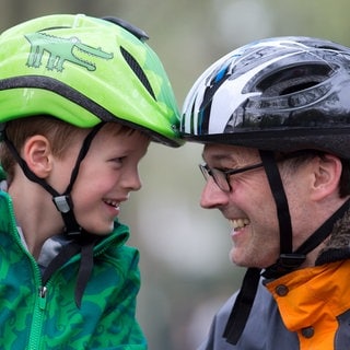 Kleiner Junge und Mann mit Helm | Sicherheitsausrüstung fürs Fahrrad: Helm, Schloss, Kleidung