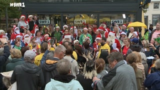 SWR1 Hitparade 2024: Stadtwette gewonnen! Mindestens 50 Menschen sollten im Weihnachtsoutfit zum Kornmarkt kommen. Zur Feier des Tages wird ein Weihnachtslied angestimmt.