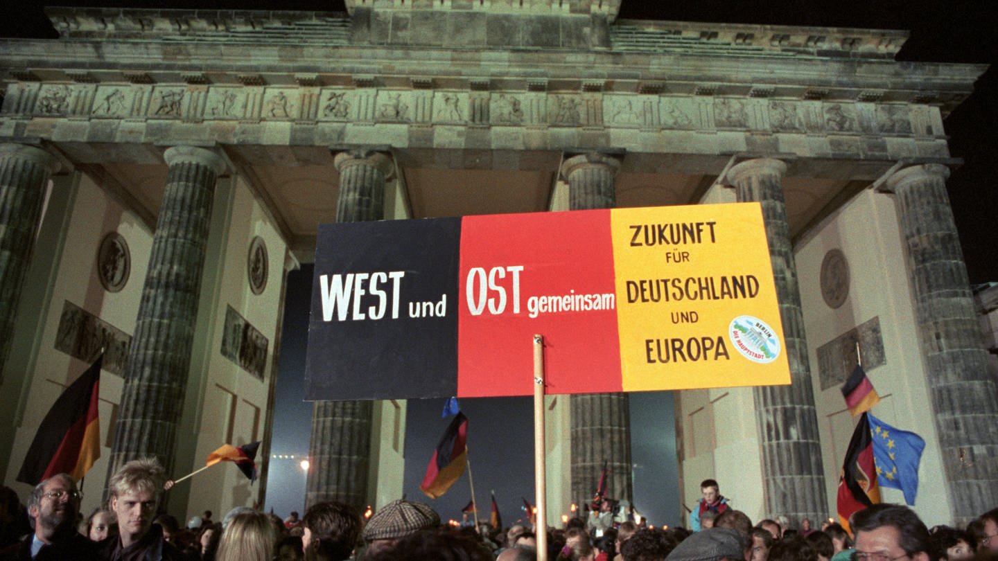 03.10.1990, Berlin: Rund eine Million Menschen feiern in der Nacht die wiedergewonnene deutsche Einheit - hier mit einem Transparent «West und Ost - Zukunft für Deutschland und Europa» vor dem Brandenburger Tor.