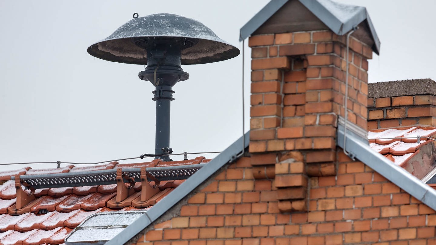 Eine Sirene ist neben einem Schornstein auf einem Hausdach montiert. Am bundesweiten Warntag kommen die Sirenen zum Einsatz.