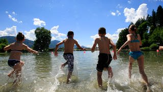 Kinder laufen in einen Bergsee hinein