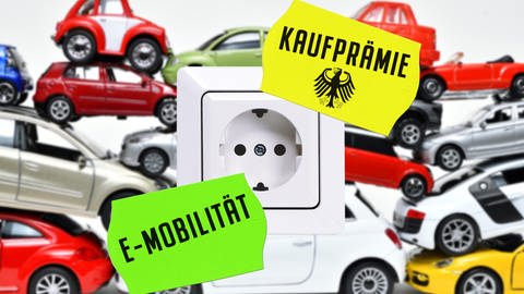 E-Autos vor einer Steckdose und den Schildern "E-Mobilität" und "Kaufprämie"