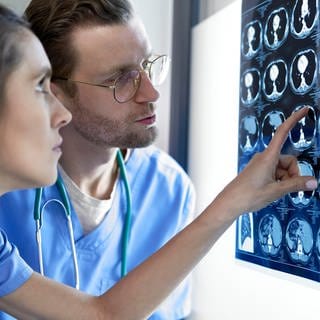 Eine Ärzt und ein Arzt schauen sich Röntgenbilder eines Schädels an
