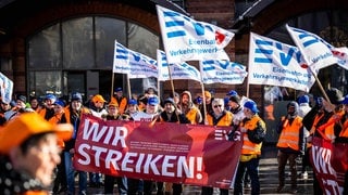 Menschen bei einer Demonstration der EVG mit Flaggen und Bannern mit der Aufschrift "Wir streiken"