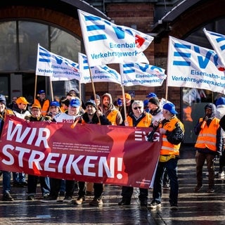 Menschen bei einer Demonstration der EVG mit Flaggen und Bannern mit der Aufschrift "Wir streiken"