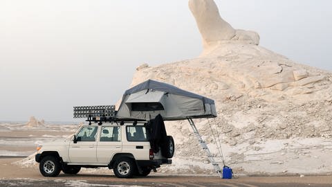 Ein Geländewagen mit Dachzelt vor einem Kreidefelsen in der weißen Wüste