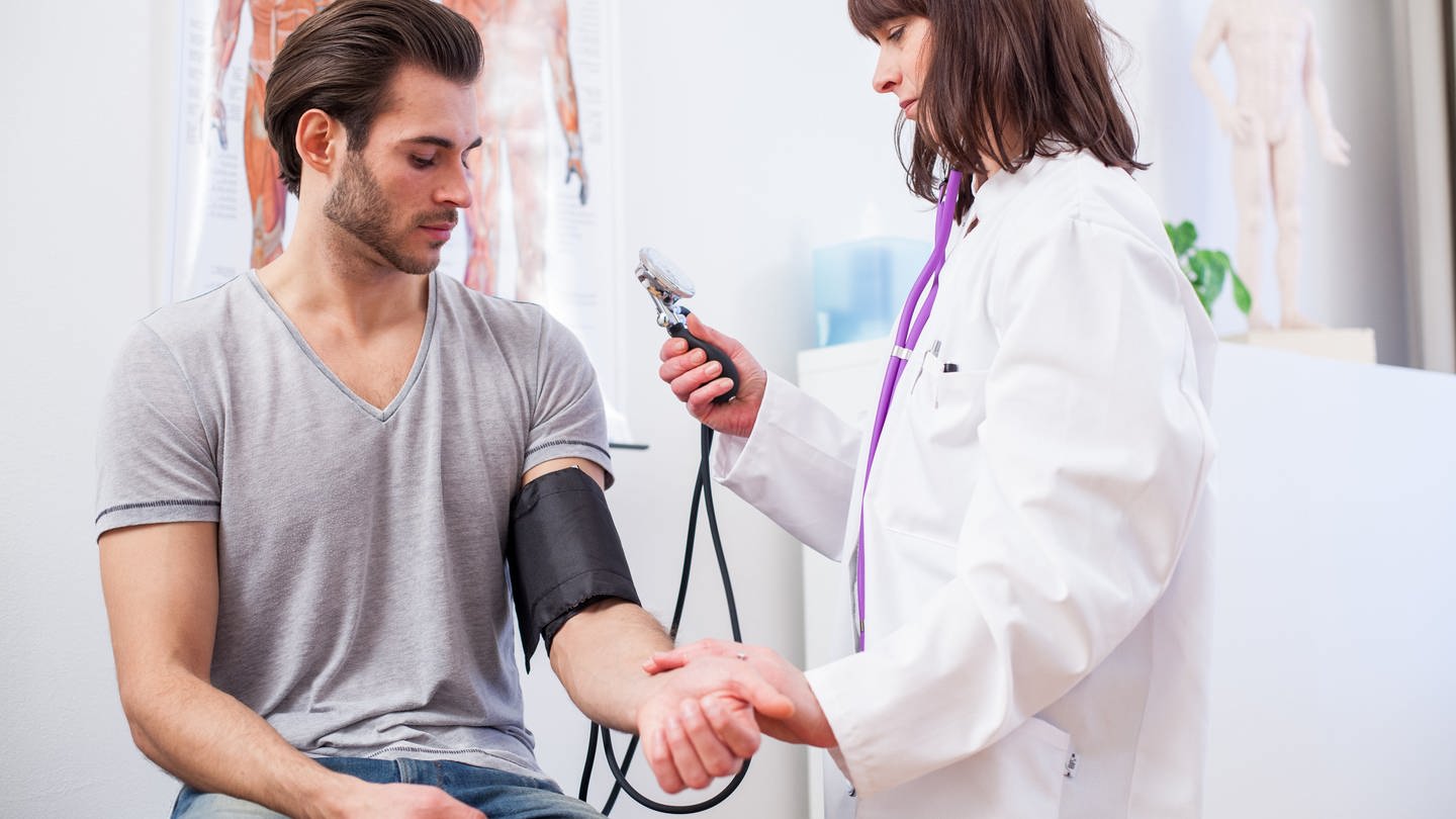 Eine Ärztin misst in einer Arztpraxis den Blutdruck ihres Patienten