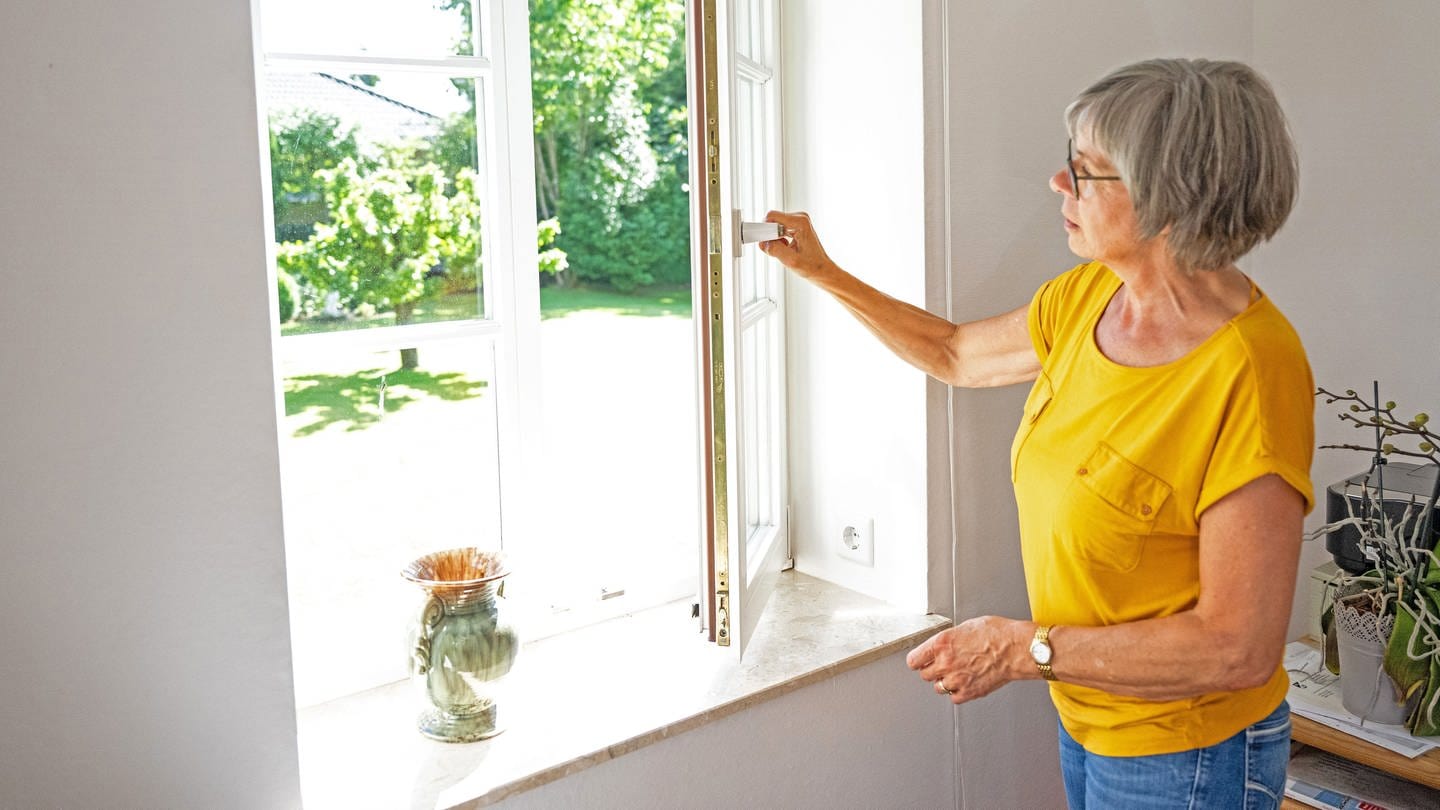 Eine Frau öffnet ein Fenster um die Wohnung zu lüften