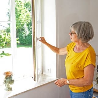 Eine Frau öffnet ein Fenster um die Wohnung zu lüften