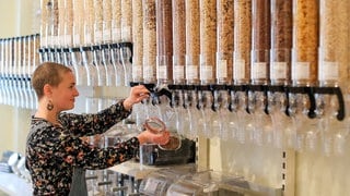 Eine Frau füllt sich in einem Unverpackt-Laden Nüsse in ein mitgebrachtes Glas