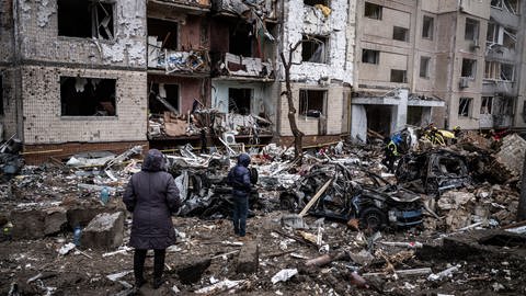 Zwei Menschen stehen vor einer zerstörten Straße in Kiew nach russischen Angriffen Russlands zum Jahresbeginn.