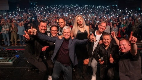 Ein unvergesslicher Abend! Die Band "Pop History" und SWR1 Musikchef Bernd Rosinus posieren für ein Abschiedsfoto vor der leuchtenden Menge.