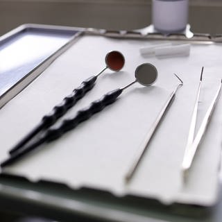 Zahnarztinstrumente liegen auf einem kleinen Tisch