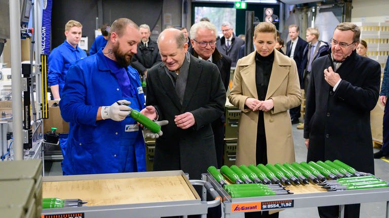 Bundeskanzler Olaf Scholz, Armin Papperger, Mette Frederiksen und Boris Pistorius besichigen eine Produktionshalle von Rheinmetall.