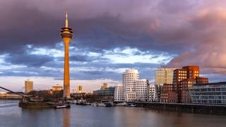 Neuer Zollhof am Medienhafen und der Rheinturm in Düsseldorf bei Sonnenuntergang. Düsseldorf ist nicht nur eine Mode- und Kunststadt, sondern auch die Heimat der Toten hosen, von Westernhagen, Doro Pesch oder Kraftwerk.