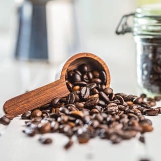 Geröstete Kaffeebohnen fallen aus einem Holzlöffel | Wie gesund ist Kaffee wirklich?