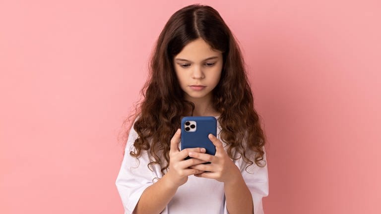 Ein Mädchen schaut auf ihr Smartphone | Wie gefährlich sind Schönheitstrends für Jugendliche?