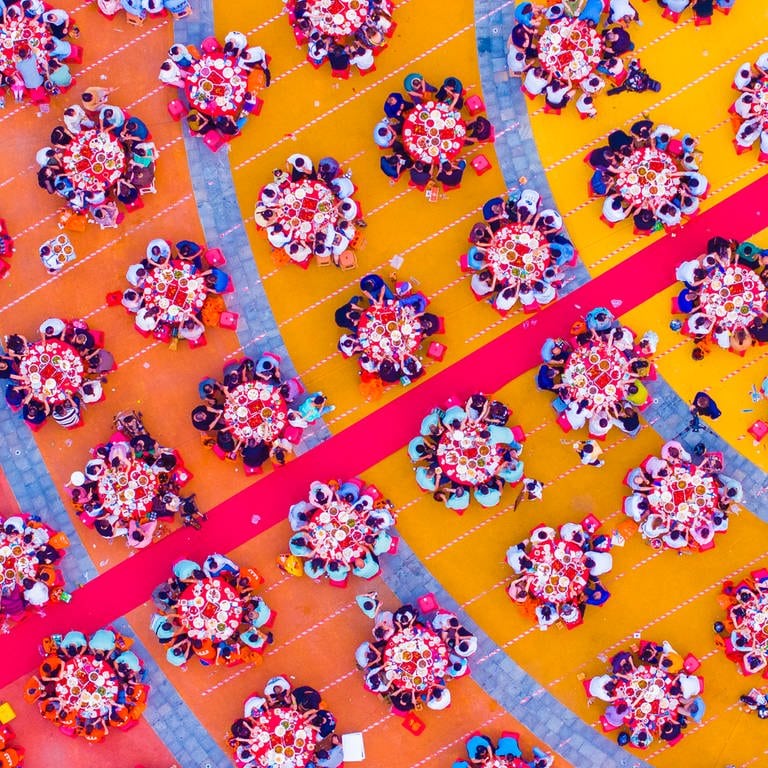 11. Juni: Ein Meer aus bunten Farben! Auf den ersten Blick könnte man glatt denken, es handelt sich hierbei um Blumen, oder ein kunstvolles Mandala - doch in Wirklichkeit sehen Sie tausende Touristen, die es sich an pinkfarbenen Tischen des Drachenbootfests in China bequem machen und frischen Fisch verköstigen.