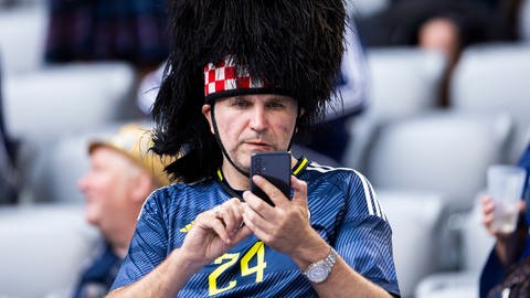 Schottland-Fan mit einem Smartphone in der Hand. | EM-Tippspiele: So tippen Sie wie ein Profi