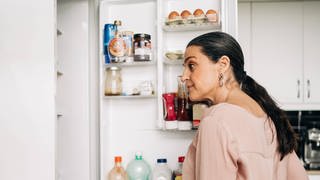 Frau schaut in einen Kühlschrank | Darauf sollten Sie bei Kühlschränken achten