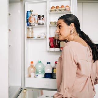 Frau schaut in einen Kühlschrank | Darauf sollten Sie bei Kühlschränken achten