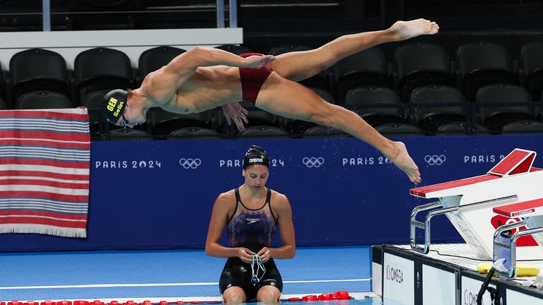 25. Juli: Die Welt steht Kopf! Ein Schwimmer der Olypmischen Spiele 2024 in Paris bewahrt die perfekte Haltung und führt während des Trainings - voller Muskelspannung - einen kontrollierten Sprung ins Wasser durch.