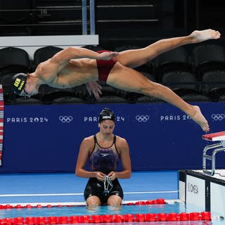 25. Juli: Die Welt steht Kopf! Ein Schwimmer der Olypmischen Spiele 2024 in Paris bewahrt die perfekte Haltung und führt während des Trainings - voller Muskelspannung - einen kontrollierten Sprung ins Wasser durch.