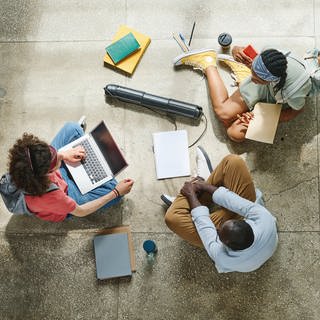 Drei Schüler sitzen mit Laptops und Schulbüchern auf dem Boden | Die beste Online Schülerzeitung Deutschlands kommt aus Neustadt