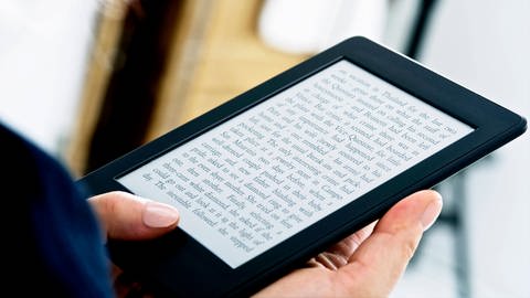 Eine Frau liest in einem E-Book-Reader (Kindle) | E-Book-Reader: Was können Tolino und Kindle?