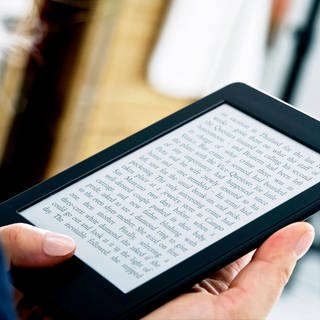 Eine Frau liest in einem E-Book-Reader (Kindle) | E-Book-Reader: Was können Tolino und Kindle?