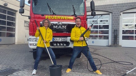 Claudia Deeg und Christan Balser waschen ein Feuerwehrauto