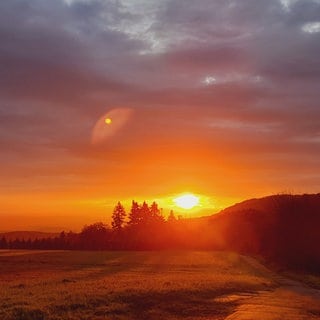 Sandra König aus Weibern schreibt uns zu ihrem Bild "Sonnenaufgang in der Vulkaneifel": "Ich war auf dem Weg zur Arbeit und ganz plötzlich war die gesamte Landschaft in ein zauberhaftes glühendes rotes Licht getaucht. Ich musste unbedingt bei der ersten Gelegenheit anhalten, um diese faszinierende Lichtstimmung festzuhalten,  die mir einen wundervollen Start in den Tag geschenkt hat."